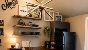 Une cuisine moderne avec un îlot central en bois, des appareils électroménagers noirs et des tabourets orange.