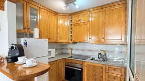Eine Küche mit Holzausstattung, Backofen, Mikrowelle und Kaffeemaschine.