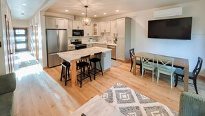 A modern kitchen with a central island, a dining area, and a ceiling fan. - The Kat's meow, 3-bedroom duplex in Nehalem (Nehalem)