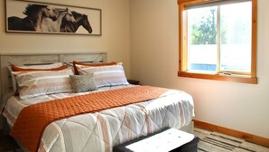 A bedroom with a bed, a window, and a painting of horses. - The Kat's meow, 3-bedroom duplex in Nehalem (Nehalem)