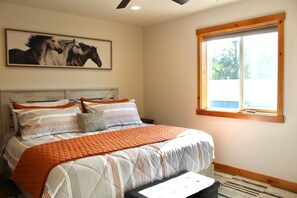 A bedroom with a bed, a window, and a painting of horses. - The Kat's meow, 3-bedroom duplex in Nehalem (Nehalem)