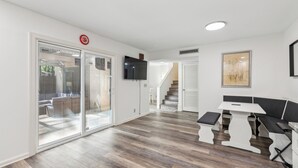 A modern interior with a flat-screen TV, a staircase, and a seating area with a table.
