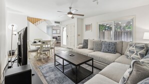 A modern living room with a sofa, coffee table, and a dining area with chairs.