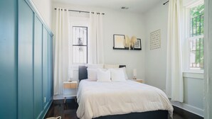 A bedroom with a bed, a window with curtains, a bedside table, and a wall-mounted picture. - Entire & Private Carriage House Near Downtown + 2 Complementary Housekeeping. (Louisville)