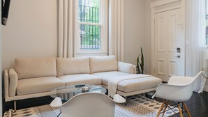 A living room with a sectional sofa, a glass coffee table, a white armchair, and a patterned rug. - Entire & Private Carriage House Near Downtown + 2 Complementary Housekeeping. (Louisville)