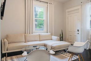 A living room with a sectional sofa, a glass coffee table, a white armchair, and a patterned rug. - Entire & Private Carriage House Near Downtown + 2 Complementary Housekeeping. (Louisville)