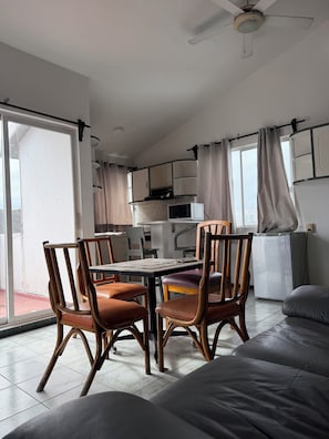 Ein Essbereich mit Tisch und Stühlen, einem Deckenventilator und einer Küche im Hintergrund.