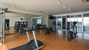 Una palestra con macchinari cardio, pesi liberi e uno specchio lungo la parete.