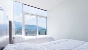 Una camera da letto con un'ampia finestra, un letto e vista sulle montagne.
