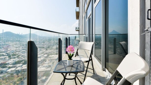 Un balcone con tavolo, sedie e una pianta in vaso.