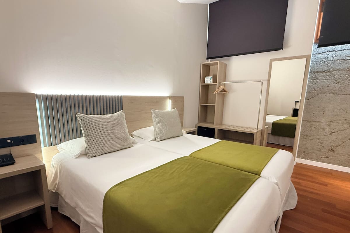 Una habitación de hotel con cama, mesitas de noche, armario y televisor de pantalla plana.