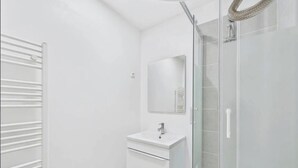 Un bagno moderno con cabina doccia in vetro, un mobile lavabo bianco con specchio e un porta asciugamani.