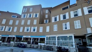 En byggnad med flera våningar, en rad fönster och en restaurang på markplan med uteservering.