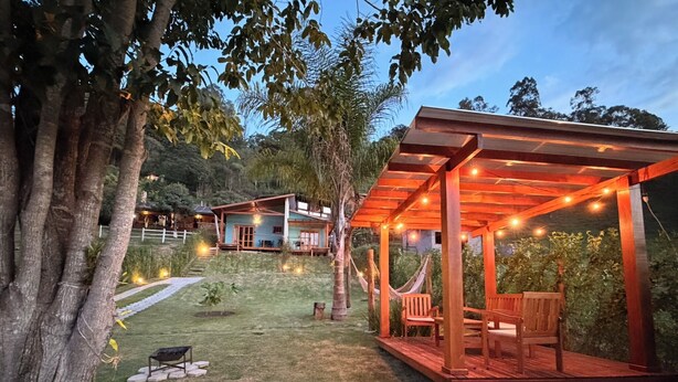 Una pérgola de madera con luces de cuerda, una hamaca y una zona de estar en un jardín.