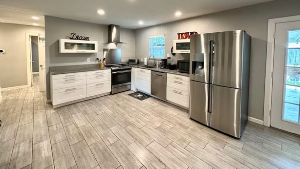 A modern kitchen with stainless steel appliances, a built-in oven, and a large island with drawers. - Children and Pet Friendly/ EV Charger/Wi-Fi/Fenced (Richland Hills)