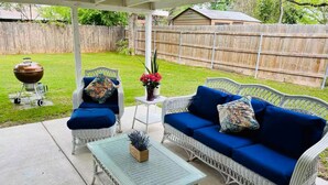 A covered patio with wicker furniture, a small table, and a barbecue grill. - Children and Pet Friendly/ EV Charger/Wi-Fi/Fenced (Richland Hills)