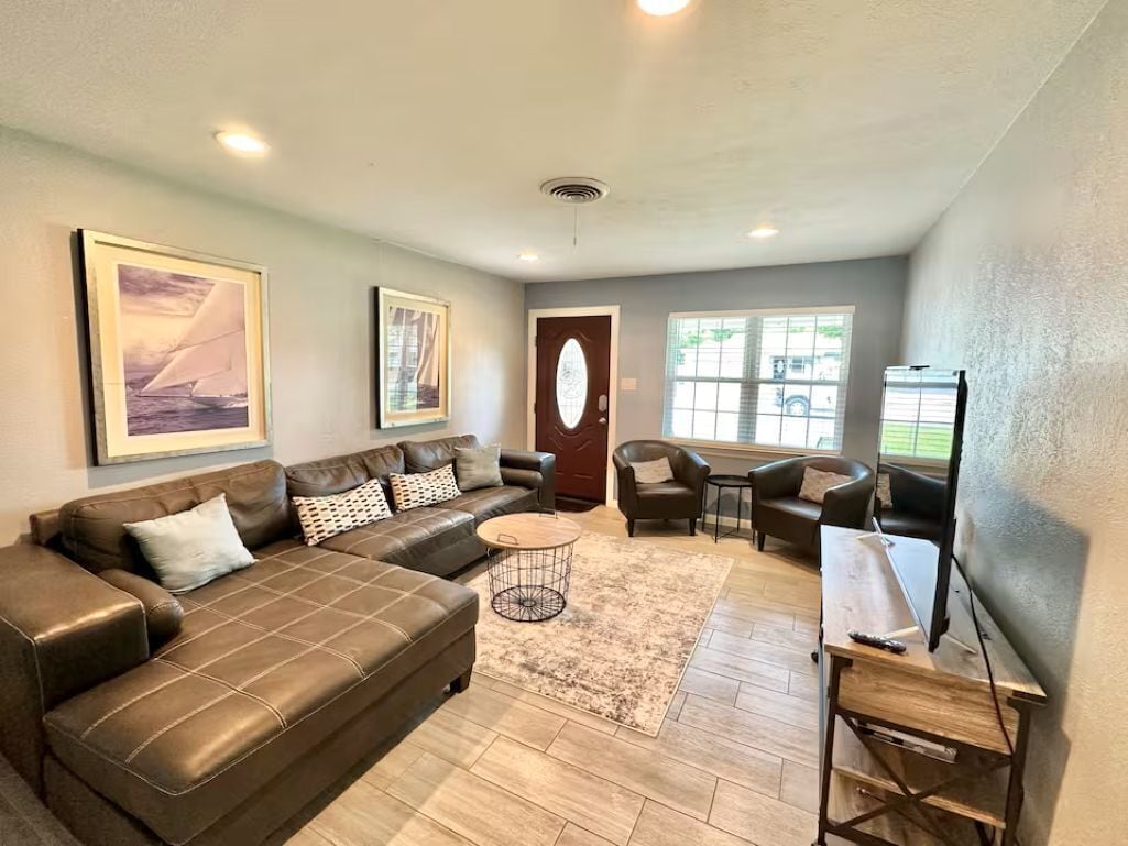 A living room with a brown leather sofa, a coffee table, and a TV stand.