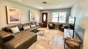A living room with a brown leather sofa, a coffee table, and a TV stand. - Children and Pet Friendly/ EV Charger/Wi-Fi/Fenced (Richland Hills)