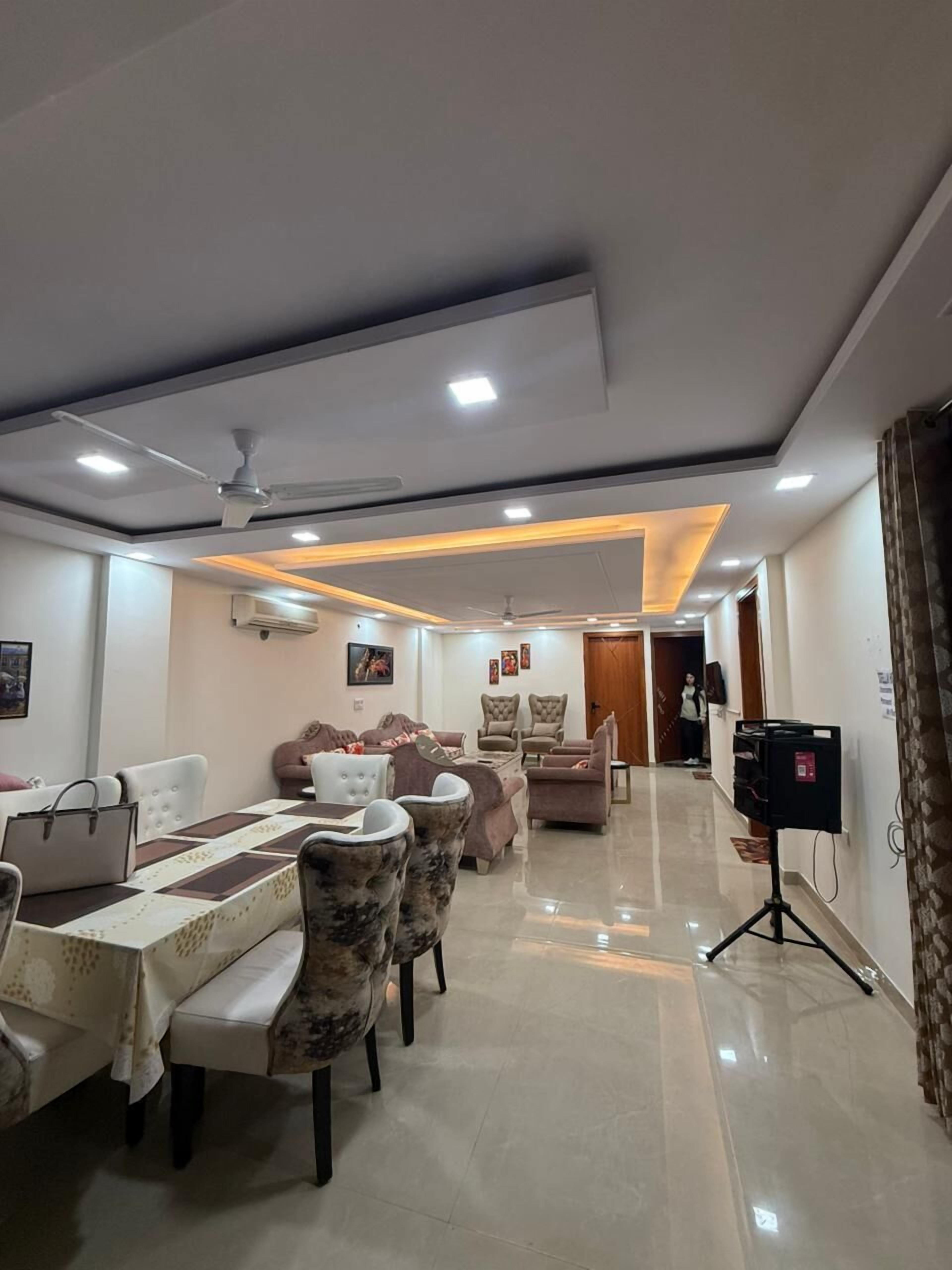 A modern living room with a dining area, ceiling fans, recessed lighting, and a polished floor.