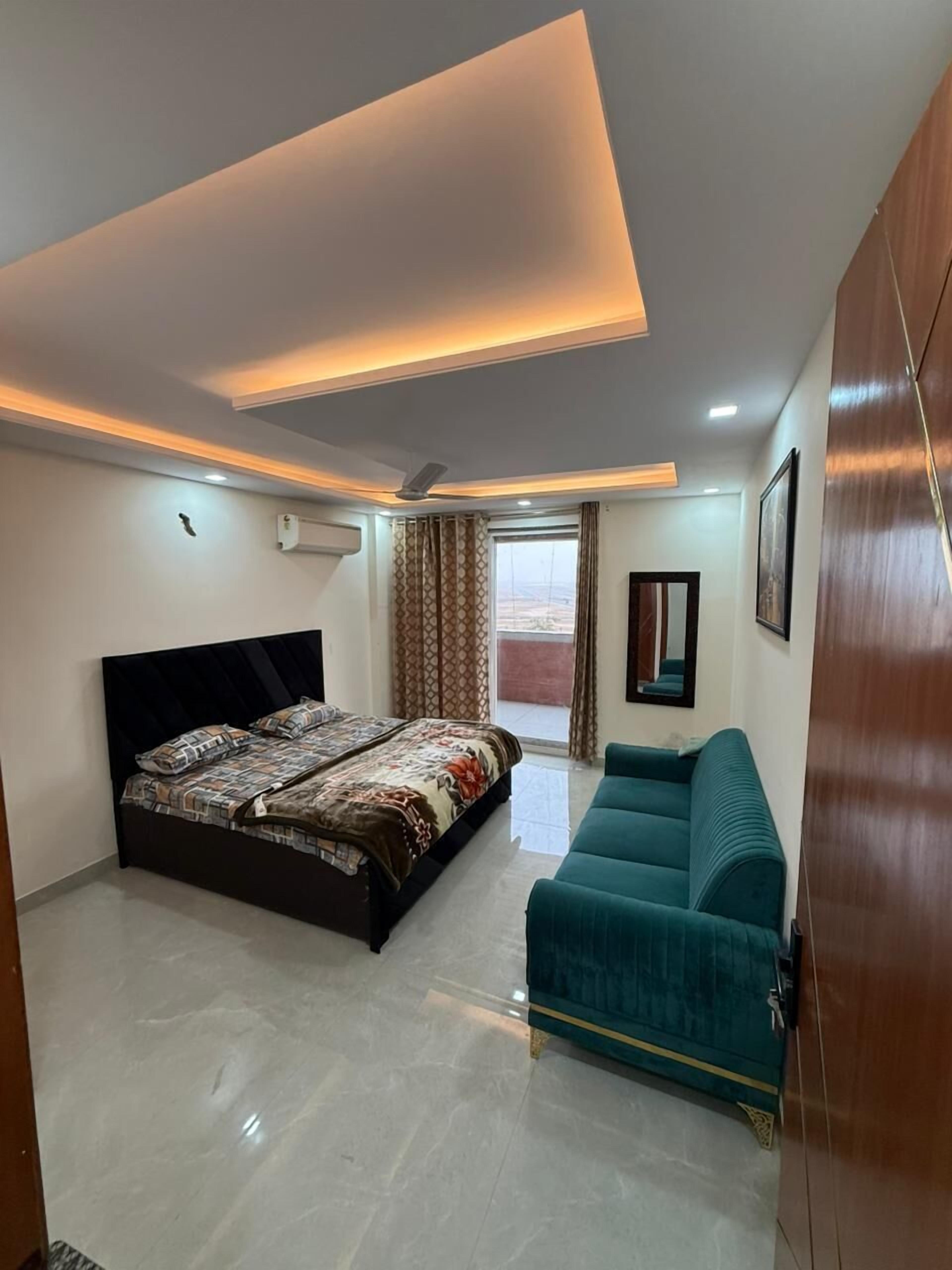 Une chambre moderne avec un lit, un canapé, un luminaire au plafond et une fenêtre.