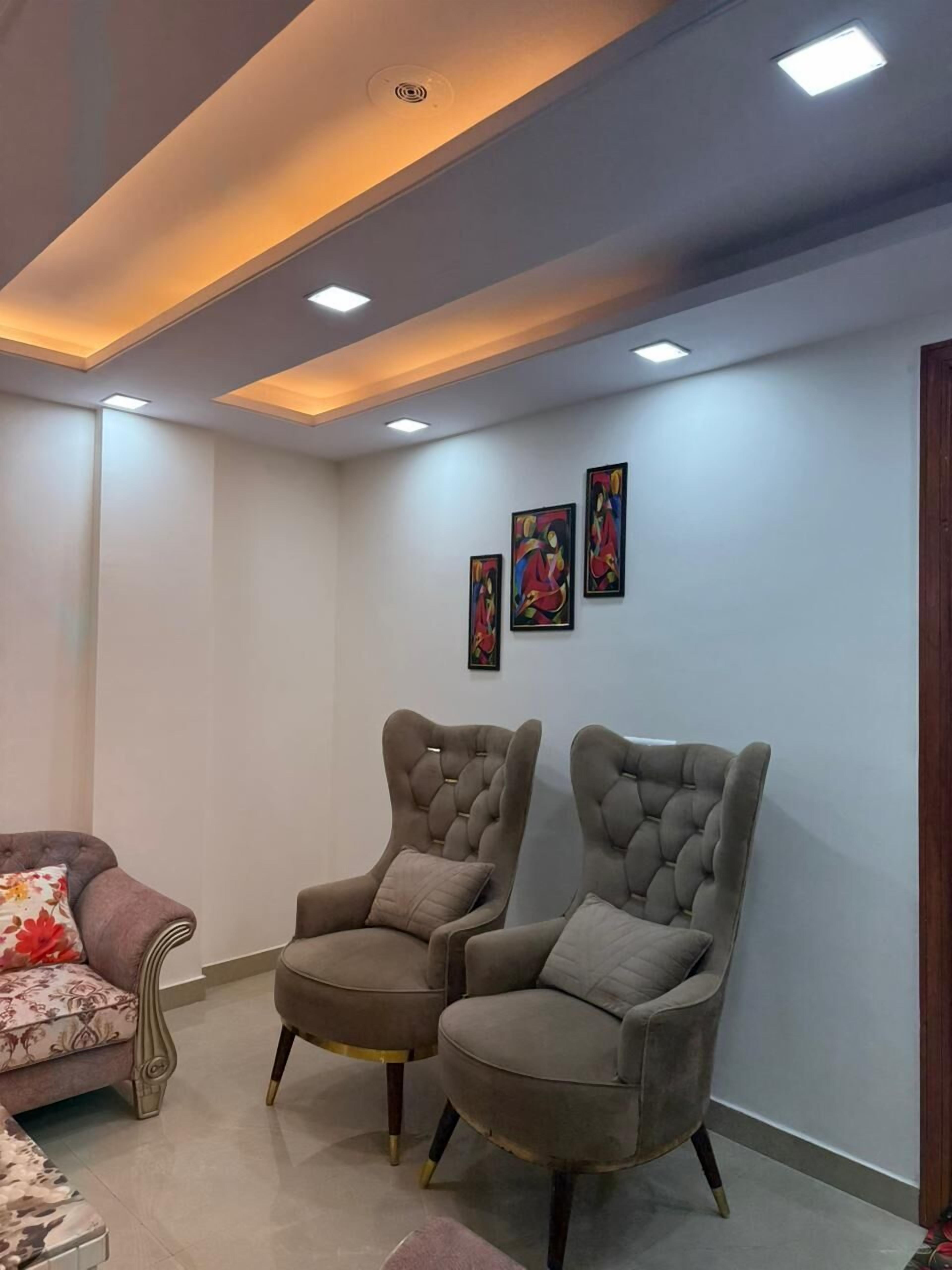 A living room with two armchairs, a sofa, and a ceiling with recessed lighting.