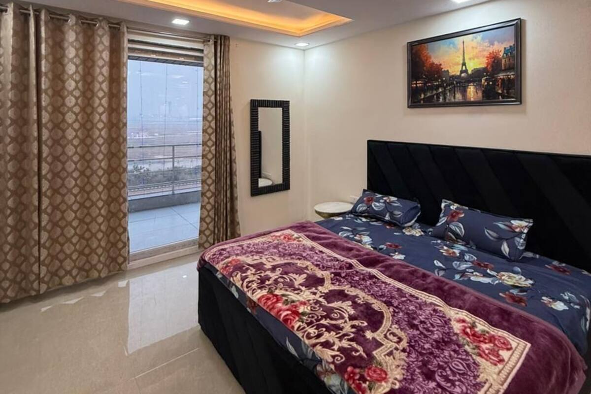 Un dormitorio con cama, ventilador de techo, un cuadro y vistas a través de una ventana.