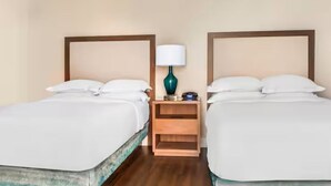Ein Hotelzimmer mit zwei Betten, einem Nachttisch mit Lampe und einem Holznachttisch zwischen den Betten.