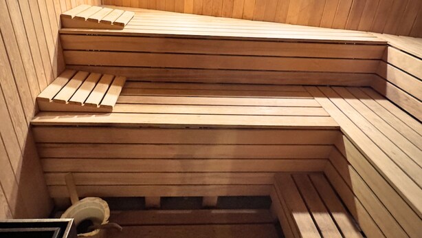 Sauna, jossa on puiset lauteet ja kaksi kattovalaisinta.