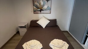 Un dormitorio con cama, mesita de noche, un cuadro y una lámpara en el techo.