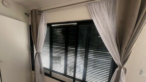 Una habitación con ventana, cortinas, radiador y puerta.