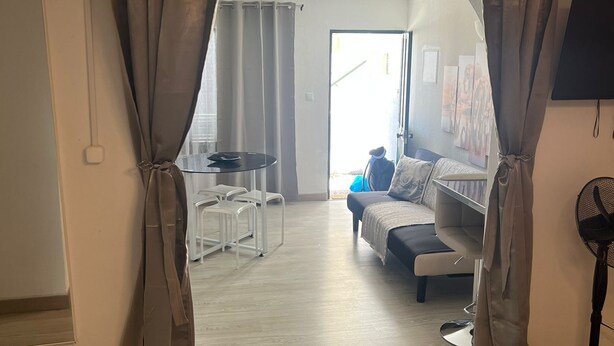 Un espacio abierto tipo salón con un sofá, una mesa de centro y un televisor montado en la pared.