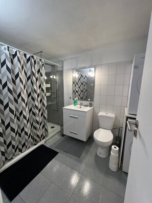 Et moderne badeværelse med bruser, toilet og håndvask.