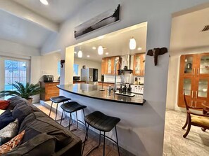 A modern kitchen with a bar area, wooden cabinets, and a large mirror. - Family Fun! Hot tub, Pool, Billiards, Gazeb (Richland Hills)