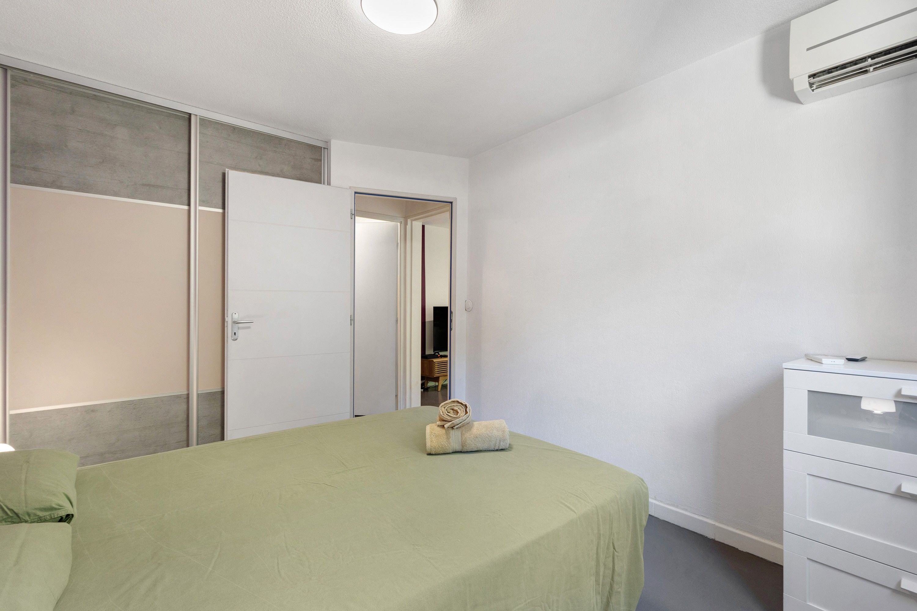 Una camera da letto con un letto, un armadio, una cassettiera e uno specchio.