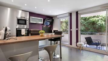 Una cucina moderna con elettrodomestici integrati, una zona pranzo con sgabelli da bar e una porta scorrevole in vetro che dà su un balcone esterno.