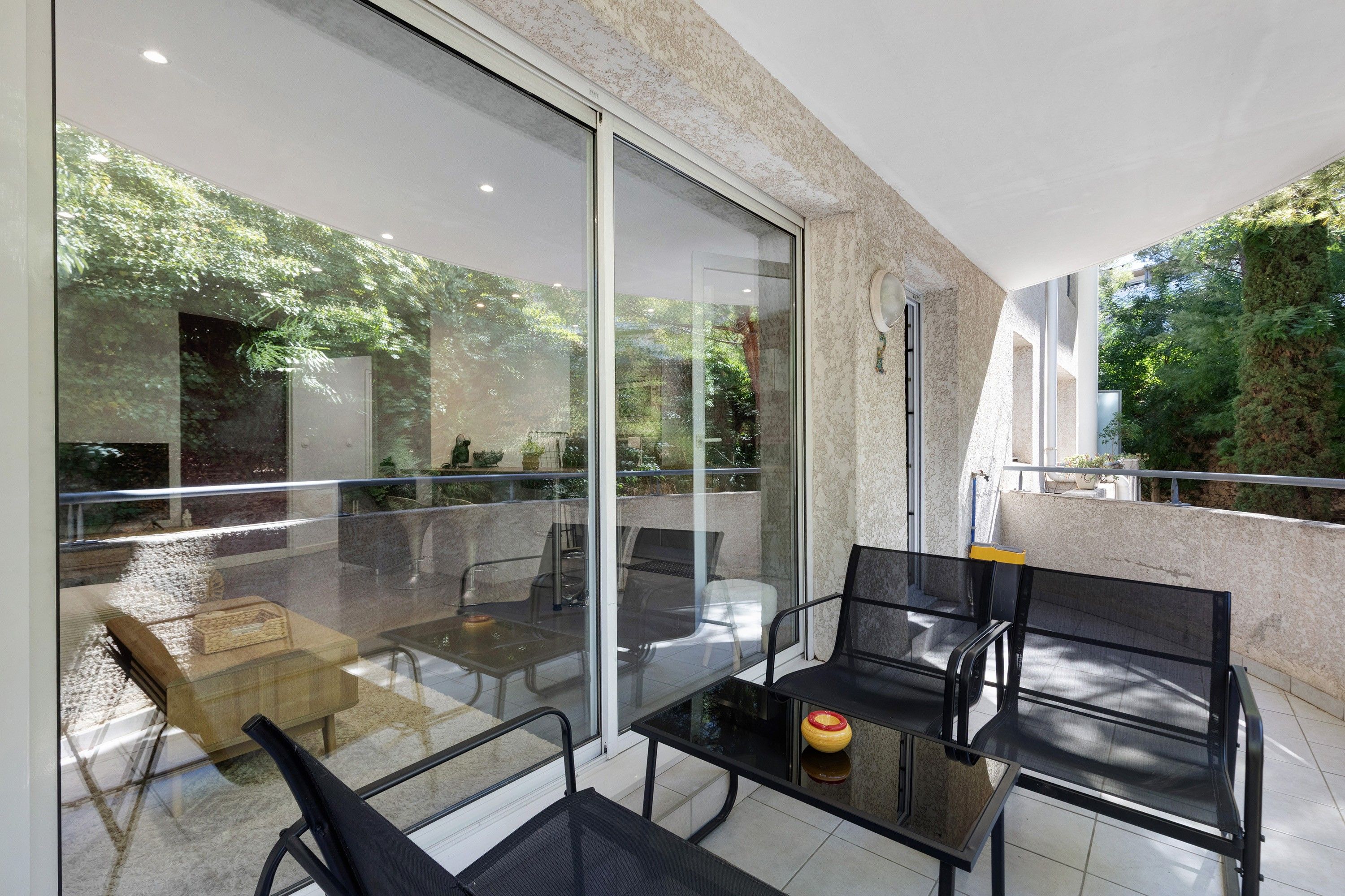 Un espace extérieur moderne, aménagé avec des murs en verre, une table et des chaises.