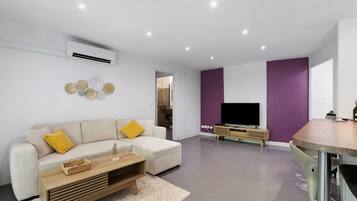 A modern living room with a sofa, coffee table, and a flat-screen TV.