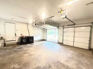 Ett garage med två stora tvättmaskiner, en dörr och en garagedörr.