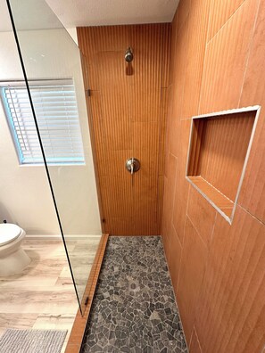 Eine Dusche mit Holztür und Fliesenboden.