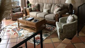 Un salon avec un mur en bois, un canapé, une table basse, deux lampes et un tableau représentant une jetée.