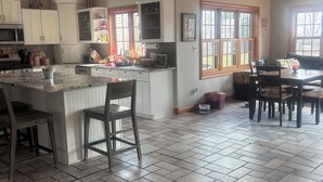 A spacious kitchen with a large island, white cabinetry, and a dining area with chairs. - Gorgeous 4-bedroom house with AC in charming Winneconne (Winneconne)