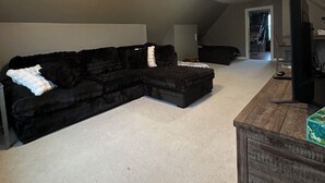 A room with a sectional sofa, a wooden desk, and a television. - Gorgeous 4-bedroom house with AC in charming Winneconne (Winneconne)