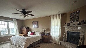 A bedroom with a bed, a ceiling fan, a fireplace, and a window. - Gorgeous 4-bedroom house with AC in charming Winneconne (Winneconne)