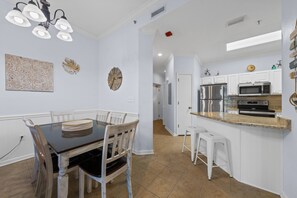 A modern kitchen with white cabinetry, a stainless steel refrigerator, and a microwave. - Phoenix East 009 - Ground-floor Gulf-front Condo - Sleeps 8 - Orange Beach, AL (Orange Beach)