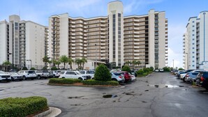 A multi-story parking lot with several cars parked, surrounded by high-rise buildings with balconies. - Phoenix East 009 - Ground-floor Gulf-front Condo - Sleeps 8 - Orange Beach, AL (Orange Beach)
