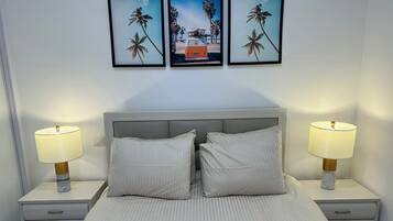 A neatly made bed with two pillows, two bedside lamps, and a nightstand with a drawer.