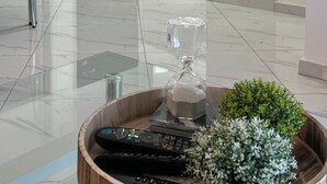 Une cuisine moderne avec des meubles blancs, un plan de travail en marbre et une table basse en verre, agrémentée de télécommandes et de plantes décoratives.