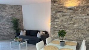 Un salon moderne comprenant un canapé, une table basse, une table à manger et une plante en pot.