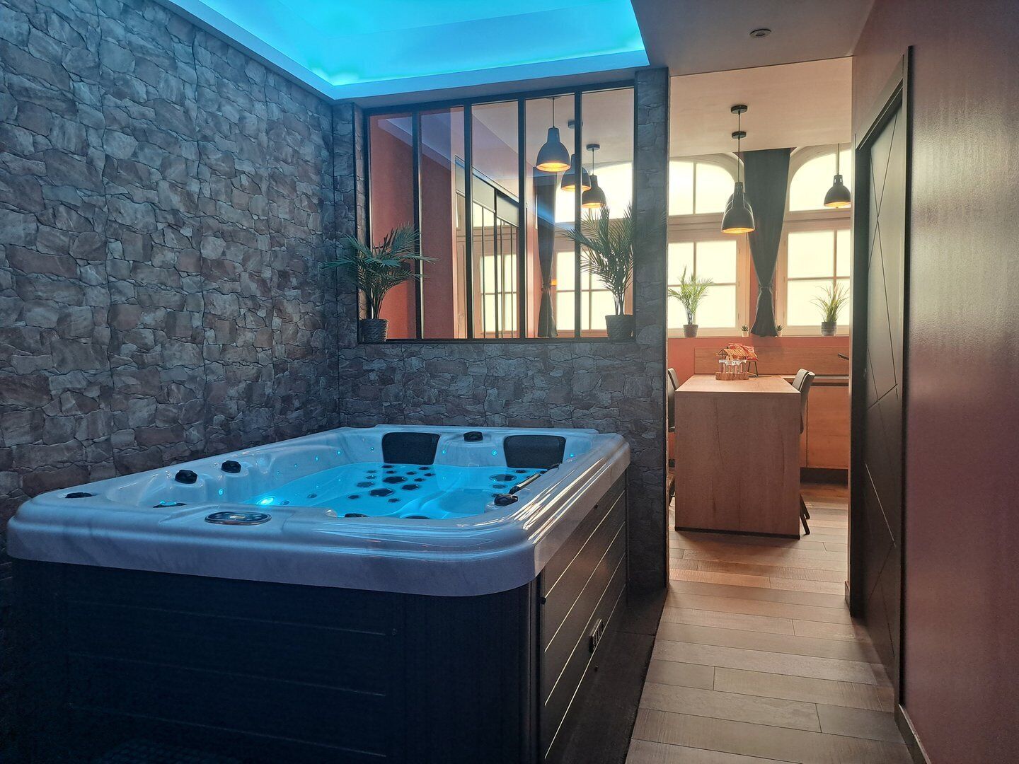 Een wellnessruimte met een bubbelbad, stenen muren en uitzicht op de binnenruimte.
