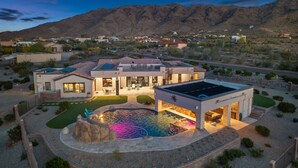 A modern house with a swimming pool, patio, and mountain views.